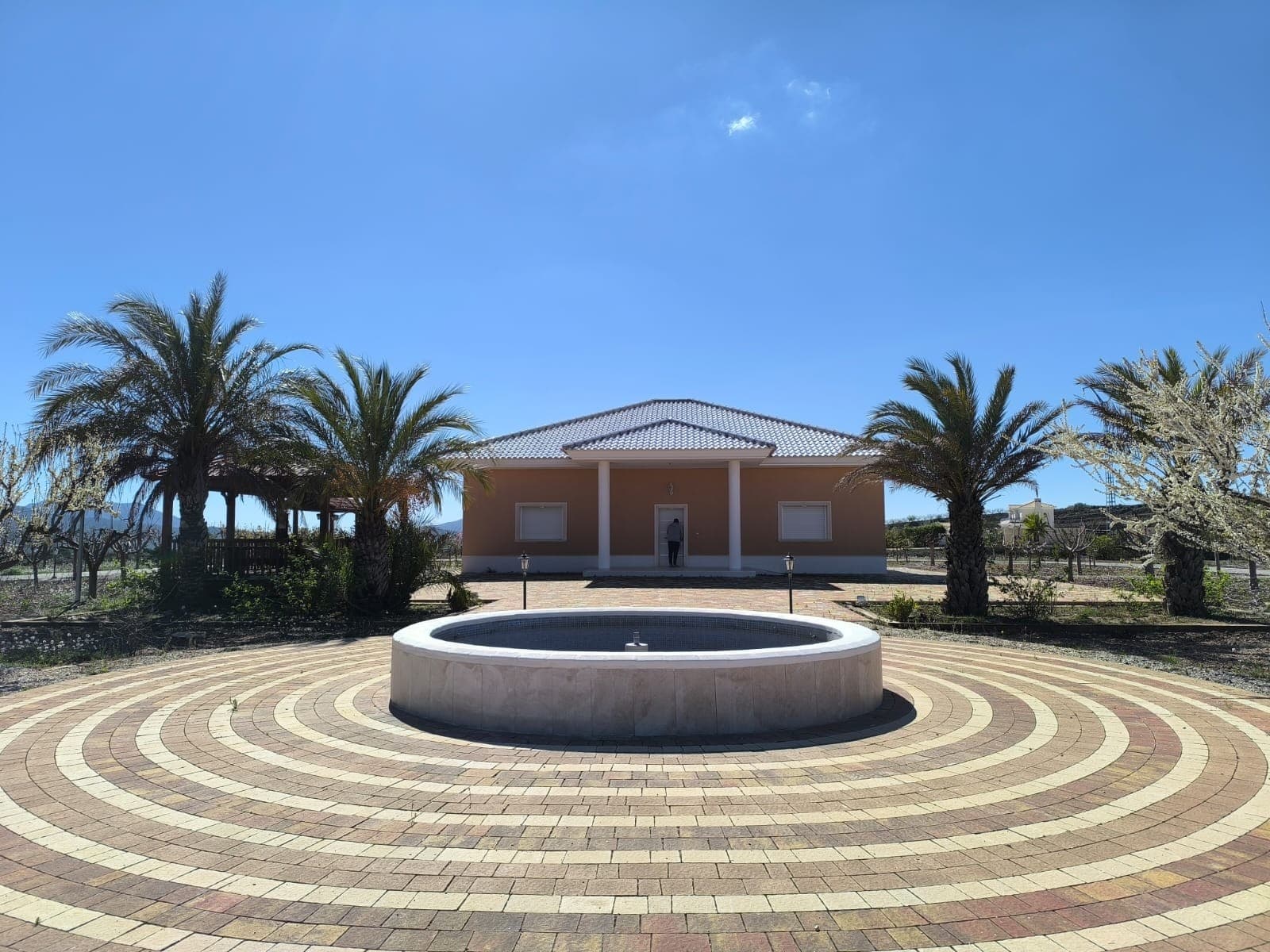 Spacious Villa Within Walking Distance to PinosoThis well-presented villa is ideally located within walking distance of Pinoso, offering the convenience of town living combined with the privacy of a detached home. The property features four bedrooms and four and a half bathrooms, making it suitable for families or those who enjoy hosting guests.Inside, the home offers comfortable and practical living spaces, with built-in wardrobes in the bedrooms and a layout designed for everyday ease. The property is connected to mains water and electricity and includes a water decalcifier system for added comfort.Outside, the villa sits within a landscaped garden with a decorative fountain, creating a pleasant and well-maintained outdoor environment. There is also a covered seating area and barbecue, ideal for dining and relaxing outdoors, along with a tool shed for storage. The property benefits from tarmac road access, making it easy to reach at all times.A project and license are already in place for the construction of a swimming pool (estimated cost €25,000), allowing the new owner to add this feature with ease.About the AreaPinoso is a lively and welcoming town known for its excellent restaurants, local markets, and strong sense of community. It offers all essential services including supermarkets, schools, sports facilities, and medical care. Surrounded by vineyards and countryside, it provides a relaxed lifestyle while still being well connected to Alicante city, the airport, and the coast. This location is ideal for both permanent living and holiday use.We have a large portfolio of properties in the Costa Blanca and Costa Calida areas, specialising in country properties, villas, fincas, building plots and design and build options in the Alicante and Murcia regions with a particular emphasis on Elda, Monovar, Pinoso, Sax, Villena, Aspe, Fortuna, Albacete and many more surrounding areas. We have been established since 2004 and have decades of experience between the team which we bring to bear to help you find and secure your new dream home. We help you every step of the way to make sure your purchase in Spain is safe and hassle free. We are not here to sell you a property, we are here to help you realise your dream and find what is right for you. With us you are in the safest hands. Contact us now to have a no obligation chat about how you too can realise your dreams.