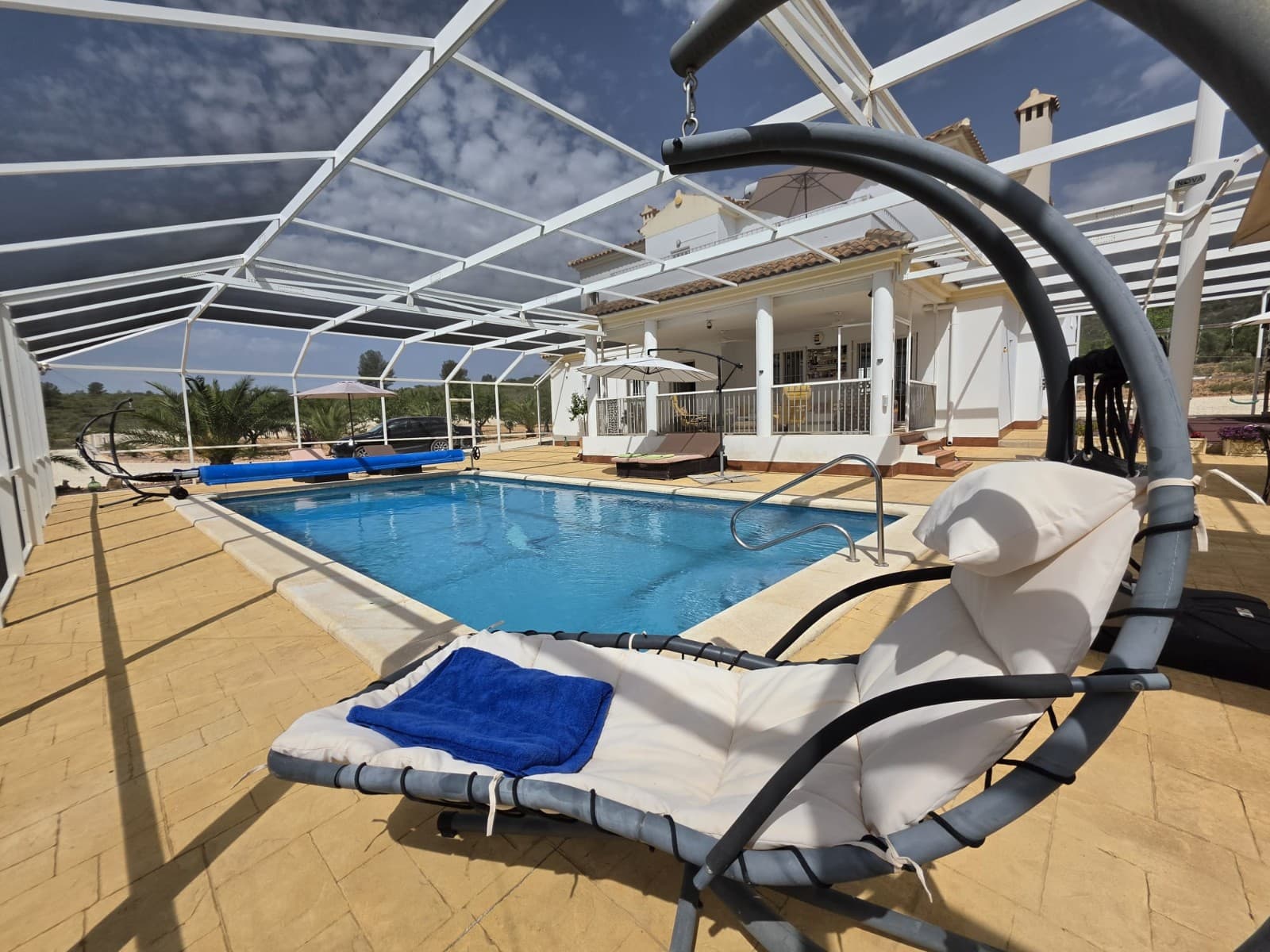 Spacious Villa with Heated Pool and Solar System in Lel, PinosoThis well-equipped villa is located in the peaceful area of Lel, near Pinoso, offering space, privacy, and a comfortable lifestyle in the countryside. The property currently features three bedrooms, all with ensuite bathrooms, and a total of five bathrooms. The home was originally designed as a four-bedroom villa and can easily be converted back if required.Inside, the villa offers generous living areas, including an extended lounge, two fireplaces, and a combination of ducted air conditioning (hot and cold) and ceiling fans throughout the house for year-round comfort. The property is fitted with fly screens and benefits from an alarm system for added security.The home is powered by mains electricity and supported by a solar system with 15 panels (500W each), helping to improve energy efficiency. Water is supplied via a 25,000-litre deposit, typically refilled every six weeks, providing a reliable and cost-effective solution.Outside, the villa sits on a fully fenced and landscaped plot with electric gates and a covered porch for outdoor living. The standout feature is the 10 x 5 metre heated swimming pool, maintained at approximately 30°C and fully enclosed within a Florida screen, which covers the pool, patio, barbecue area, and children's play area. This creates a comfortable outdoor space protected from flies during harvest season and other insects.The outdoor area is designed for both relaxation and entertaining, featuring a barbecue area with a pizza oven, an outside toilet, and a children's playground with climbing frame. The grounds include an orchard with almond trees and irrigation pipes throughout the plot. A local farmer maintains the land and trees at no cost in exchange for the crops.The garage building is split into a garage space and a workshop, and also includes an upper floor currently used as storage and a dressing room. This building offers further potential and could be converted into a self-contained guest annexe if desired.The property is set in a quiet area with complete privacy and enjoys open views across the valley, vineyards, and orchards. While there are neighbours in the surrounding area, the villa itself remains private and secluded. The entire plot is secure and ideal for walking, outdoor activities, or simply enjoying the natural surroundings.About the Area Lel is a peaceful rural area just a short drive from Pinoso, a lively inland town known for its excellent restaurants, local wines, and welcoming community. Pinoso offers all essential services including supermarkets, schools, and medical facilities, and is less than 10 minutes away. The nearest bar or restaurant is approximately 3–4 km from the property. The surrounding countryside is ideal for walking, hiking, and outdoor living, while Alicante city, the airport, and the coast are all within comfortable driving distance. This location offers a perfect balance of privacy, nature, and convenience.We have a large portfolio of properties in the Costa Blanca and Costa Calida areas, specialising in country properties, villas, fincas, building plots and design and build options in the Alicante and Murcia regions with a particular emphasis on Elda, Monovar, Pinoso, Sax, Villena, Aspe, Fortuna, Albacete and many more surrounding areas. We have been established since 2004 and have decades of experience between the team which we bring to bear to help you find and secure your new dream home. We help you every step of the way to make sure your purchase in Spain is safe and hassle free. We are not here to sell you a property, we are here to help you realise your dream and find what is right for you. With us you are in the safest hands. Contact us now to have a no obligation chat about how you too can realise your dreams.