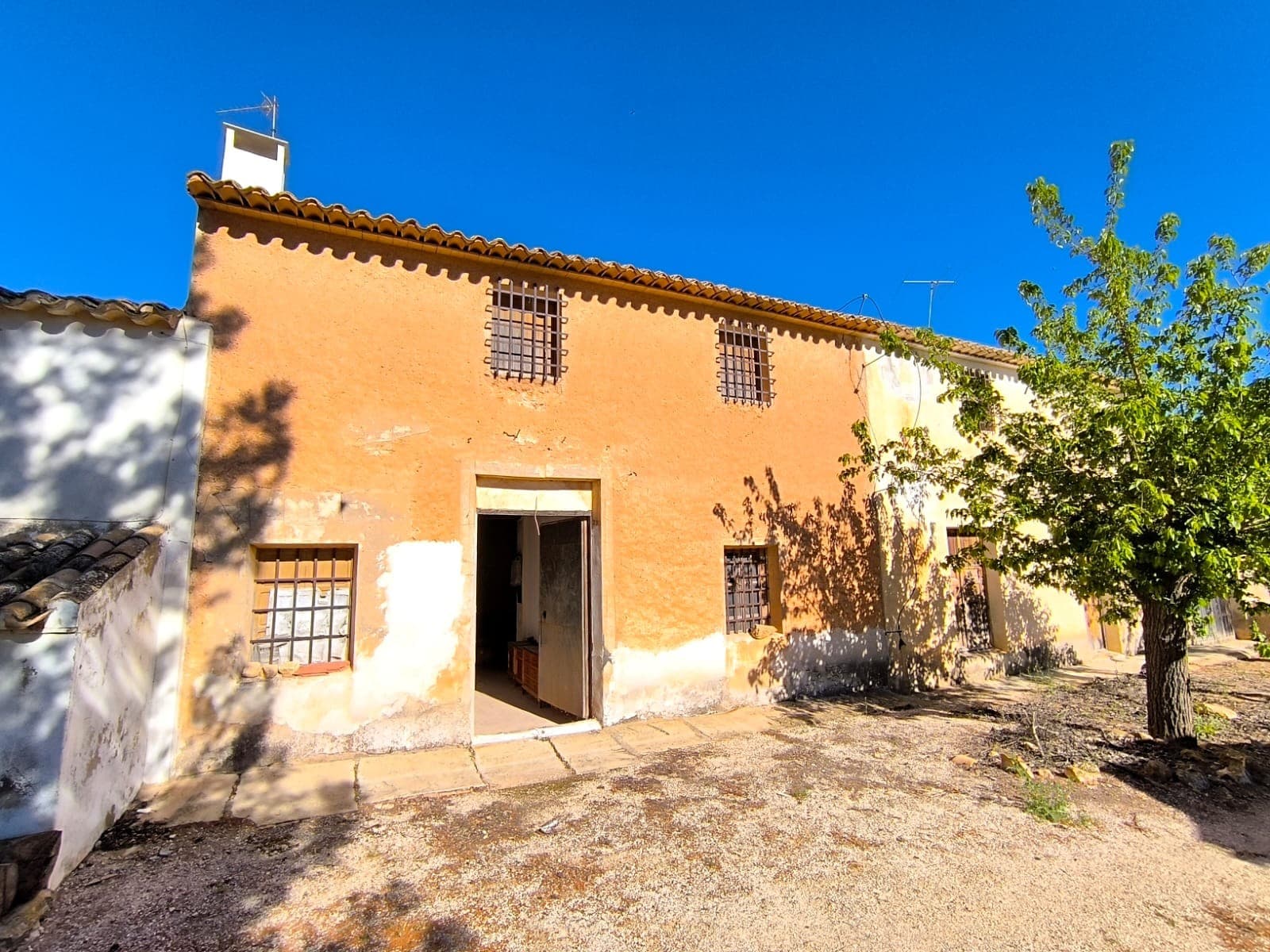 Attached country house with authentic rustic spirit, surprisingly spacious on the inside, offering approximately 125 years of history. Solid, thick stone walls and a sound roof provide a reliable structure. Traditional features include exposed wooden beams, stone pillars, and a large fireplace, creating a warm and characterful atmosphere. The property comprises a two-floor living unit, a patio with storage and a water deposit, rooms for animals, and a large garage, offering plenty of potential for various uses.The house is not currently habitable and requires renovation, presenting an opportunity to design and restore a unique countryside home while preserving its original charm. The walls remain structurally sound.The property also includes land, just a few metres from the house: olives grove of 1500 m2 with century old trees in full production, and a garden with fruit trees of 1200 m2, perfect for enjoying outdoor living and a self-sufficient lifestyle. Convenient access via a tarmac road ensures easy year-round reach.Located just 10 km, 10 minutes from town, in a peaceful and tranquil countryside setting with open surroundings. Contact us for a commented walkthrough video.We offer more lands in the same area, and also the adjacent country house. Contact us for more info!About the area: Yecla is a charming and historic town of app. 35000 inhabitants, located in the region of Murcia. It is renowned for its award-winning wines, historical landmarks, and vibrant local culture. The surrounding natural landscapes of scenic mountains, vineyards and almond groves provide opportunities for outdoor activities, while the town itself offers all necessary services, including hospital, schools, shops, restaurants, and other services. With a friendly local community, lively markets, excellent gastronomy, and easy access to nature, Yecla is an ideal location for those seeking authentic Spanish lifestyle - just about an hour from the coast and Alicante airport.About us: We have a large portfolio of properties in the Costa Blanca and Costa Calida areas, specialising in country properties, villas, fincas, building plots and design and build options in the Alicante and Murcia regions with a particular emphasis on Yecla, Novelda, Elda, Monovar, Pinoso, Sax, Villena, Aspe, Fortuna, Jumilla, Abanilla, and many more surrounding areas. We have been established since 2004 and have decades of experience between the team which we bring to bear to help you find and secure your new dream home. We help you every step of the way to make sure your purchase in Spain is safe and hassle free. We are not here to sell you a property, we are here to help you realise your dream and find what is right for you. With us you are in the safest hands. Contact us now to have a no obligation chat about how you too can realise your dreams.